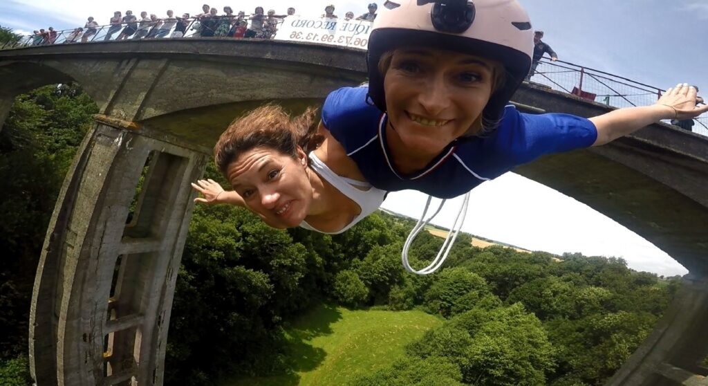 Participants réalisant un saut à l’élastique en duo depuis le viaduc de Saint-Georges-le-Gaultier au-dessus d’une vallée verdoyante